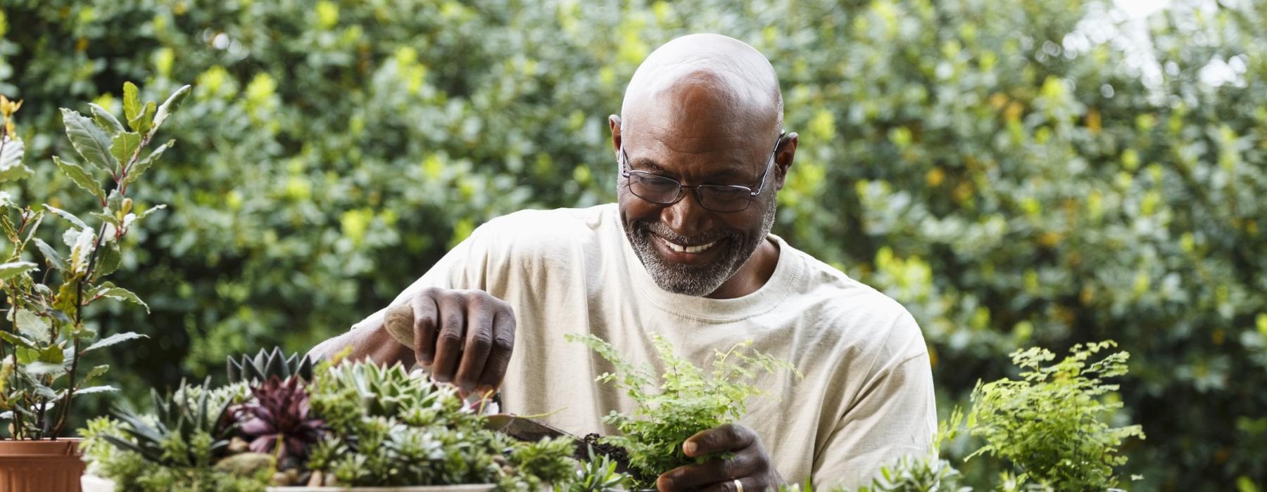 a man sitting at a table with plants and a potted plant